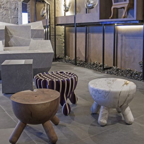 Poltrona revestida com lastras de porcelanato e banco esculpido em mármore da designer Karol Suguikawa | Foto: Renato Navarro